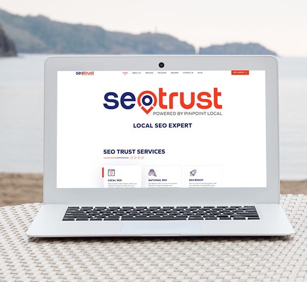 A laptop with the SEO Trust logo on it sitting on a beach, representing the expertise of the best SEO company.