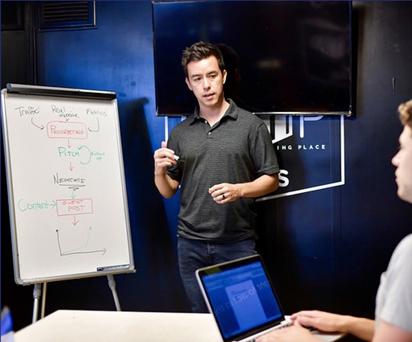 A man is giving a presentation in front of a whiteboard about digital marketing strategies, emphasizing the importance of local SEO expertise.